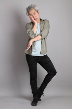 Gri arka planda duran 40 'lı yılların Asyalı, şık, sıradan elbiseli adamı.. 