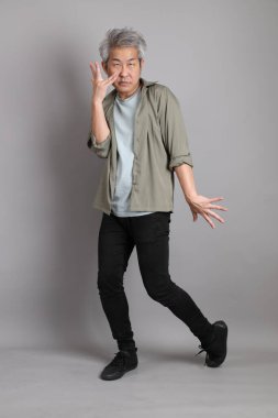 Gri arka planda duran 40 'lı yılların Asyalı, şık, sıradan elbiseli adamı.. 