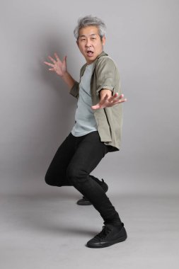 Gri arka planda duran 40 'lı yılların Asyalı, şık, sıradan elbiseli adamı.. 