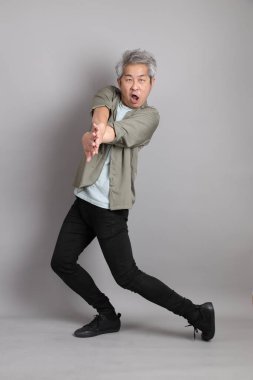 Gri arka planda duran 40 'lı yılların Asyalı, şık, sıradan elbiseli adamı.. 