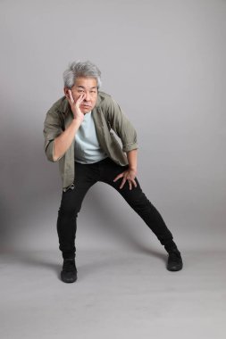 Gri arka planda duran 40 'lı yılların Asyalı, şık, sıradan elbiseli adamı.. 