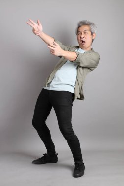 Gri arka planda duran 40 'lı yılların Asyalı, şık, sıradan elbiseli adamı.. 