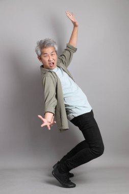 Gri arka planda duran 40 'lı yılların Asyalı, şık, sıradan elbiseli adamı.. 