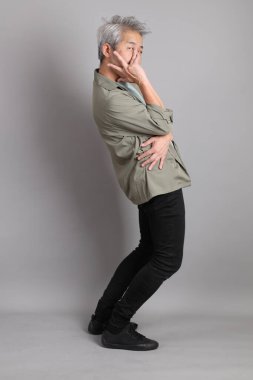 Gri arka planda duran 40 'lı yılların Asyalı, şık, sıradan elbiseli adamı.. 