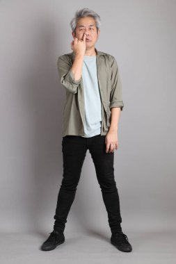 Gri arka planda duran 40 'lı yılların Asyalı, şık, sıradan elbiseli adamı.. 