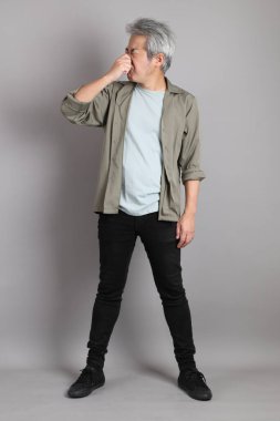 Gri arka planda duran 40 'lı yılların Asyalı, şık, sıradan elbiseli adamı.. 