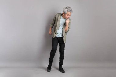 Gri arka planda duran 40 'lı yılların Asyalı, şık, sıradan elbiseli adamı.. 