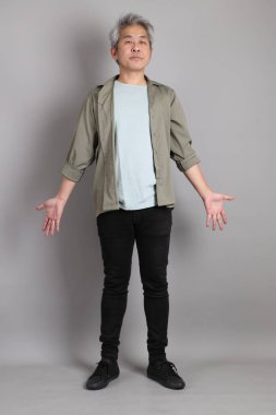 Gri arka planda duran 40 'lı yılların Asyalı, şık, sıradan elbiseli adamı.. 