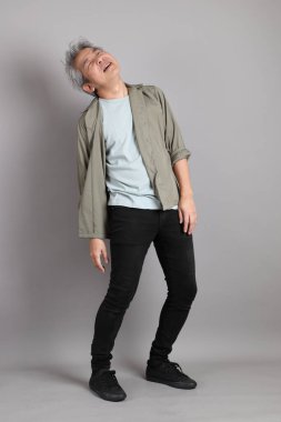 Gri arka planda duran 40 'lı yılların Asyalı, şık, sıradan elbiseli adamı.. 