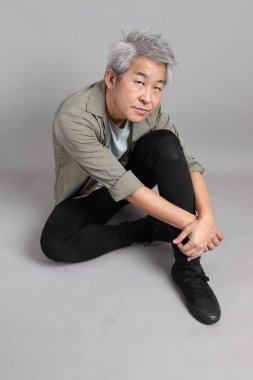 Gri arka planda oturan 40 'lı yaşlardaki Asyalı adam.. 