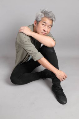 Gri arka planda oturan 40 'lı yaşlardaki Asyalı adam.. 