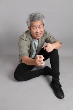 Gri arka planda oturan 40 'lı yaşlardaki Asyalı adam.. 