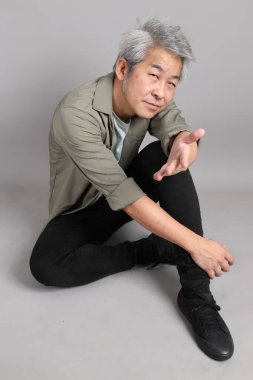 Gri arka planda oturan 40 'lı yaşlardaki Asyalı adam.. 