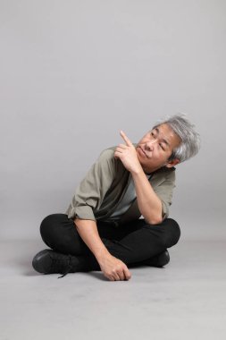 Gri arka planda oturan 40 'lı yaşlardaki Asyalı adam.. 