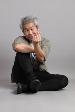 Gri arka planda oturan 40 'lı yaşlardaki Asyalı adam.. 