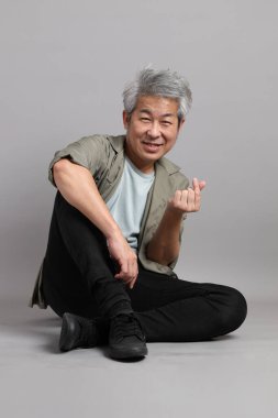 Gri arka planda oturan 40 'lı yaşlardaki Asyalı adam.. 