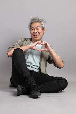 Gri arka planda oturan 40 'lı yaşlardaki Asyalı adam.. 