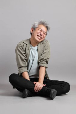 Gri arka planda oturan 40 'lı yaşlardaki Asyalı adam.. 