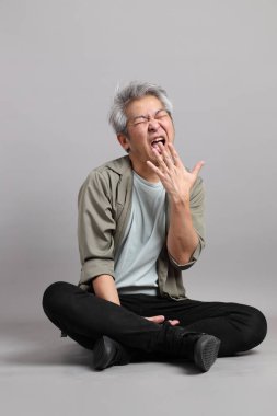 Gri arka planda oturan 40 'lı yaşlardaki Asyalı adam.. 