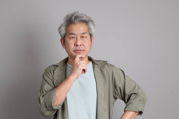 The 40s Asian man with smart casual clothes standing on the grey background. 