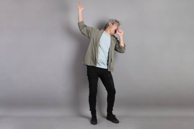 Gri arka planda duran 40 'lı yılların Asyalı, şık, sıradan elbiseli adamı.. 