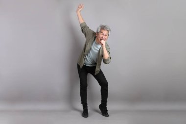 Gri arka planda duran 40 'lı yılların Asyalı, şık, sıradan elbiseli adamı.. 