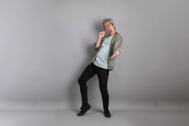 Gri arka planda duran 40 'lı yılların Asyalı, şık, sıradan elbiseli adamı.. 