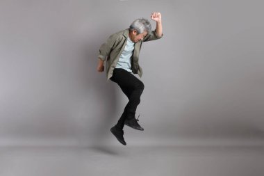 Gri arka planda duran 40 'lı yılların Asyalı, şık, sıradan elbiseli adamı.. 