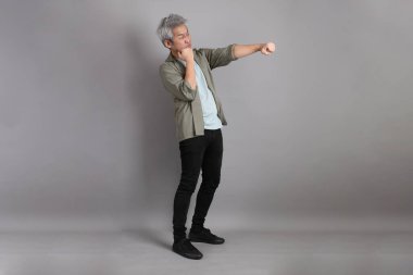 Gri arka planda duran 40 'lı yılların Asyalı, şık, sıradan elbiseli adamı.. 