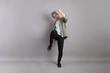 Gri arka planda duran 40 'lı yılların Asyalı, şık, sıradan elbiseli adamı.. 