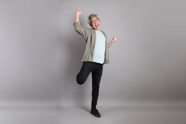 Gri arka planda duran 40 'lı yılların Asyalı, şık, sıradan elbiseli adamı.. 