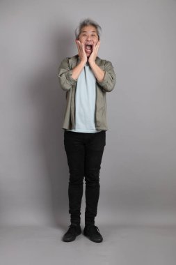 Gri arka planda duran 40 'lı yılların Asyalı, şık, sıradan elbiseli adamı.. 