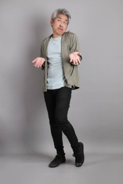 Gri arka planda duran 40 'lı yılların Asyalı, şık, sıradan elbiseli adamı.. 