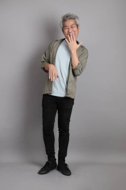 Gri arka planda duran 40 'lı yılların Asyalı, şık, sıradan elbiseli adamı.. 