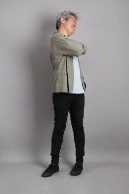 Gri arka planda duran 40 'lı yılların Asyalı, şık, sıradan elbiseli adamı.. 