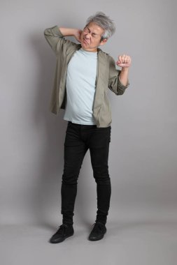 Gri arka planda duran 40 'lı yılların Asyalı, şık, sıradan elbiseli adamı.. 