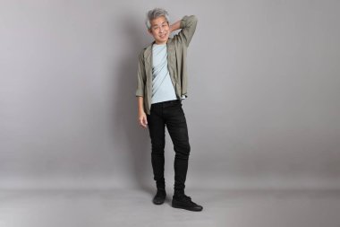 Gri arka planda duran 40 'lı yılların Asyalı, şık, sıradan elbiseli adamı.. 