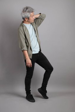 Gri arka planda duran 40 'lı yılların Asyalı, şık, sıradan elbiseli adamı.. 