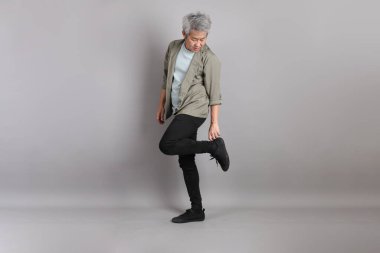 Gri arka planda duran 40 'lı yılların Asyalı, şık, sıradan elbiseli adamı.. 