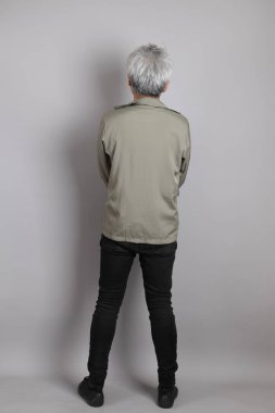 Gri arka planda duran 40 'lı yılların Asyalı, şık, sıradan elbiseli adamı.. 