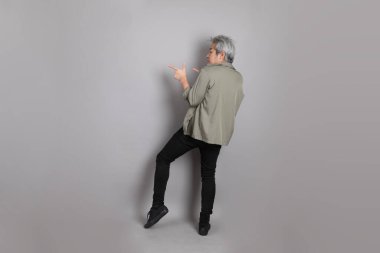 Gri arka planda duran 40 'lı yılların Asyalı, şık, sıradan elbiseli adamı.. 