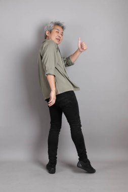 Gri arka planda duran 40 'lı yılların Asyalı, şık, sıradan elbiseli adamı.. 