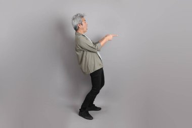 Gri arka planda duran 40 'lı yılların Asyalı, şık, sıradan elbiseli adamı.. 