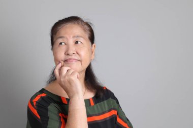 Gri arka planda günlük giysileri olan 70 'lerin son sınıf Çinli kadını..