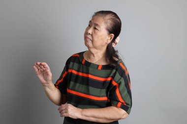 Gri arka planda günlük giysileri olan 70 'lerin son sınıf Çinli kadını..