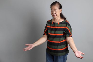 Gri arka planda günlük giysileri olan 70 'lerin son sınıf Çinli kadını..