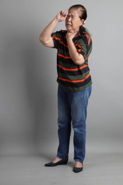 Gri arka planda günlük giysileri olan 70 'lerin son sınıf Çinli kadını..