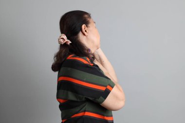 Gri arka planda günlük giysileri olan 70 'lerin son sınıf Çinli kadını..