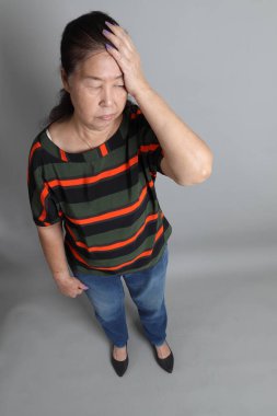 Gri arka planda günlük giysileri olan 70 'lerin son sınıf Çinli kadını..