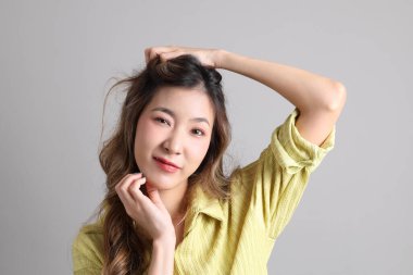 Gri arka planda sıradan giyinmiş Asyalı kadın..